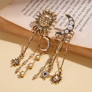 Retro gold earrings with sun, moon, star charms and pearls on vintage book background