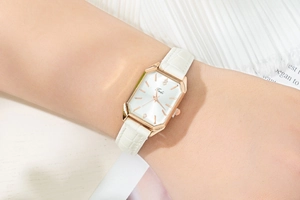Close-up of a women's square quartz watch with rose gold case and white leather strap