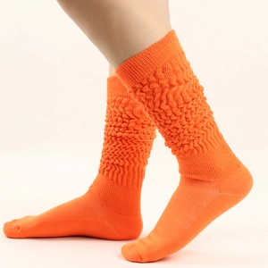 Close-up of bright orange slouch socks with textured knit wave pattern on model