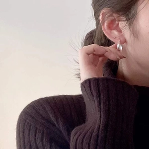 Close-up of minimalist S925 sterling silver hoop earrings worn on a model's ear