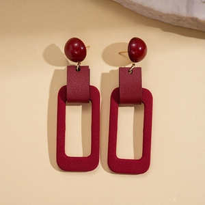 Detail view of burgundy resin and leather drop earrings with unique fabric texture pendant