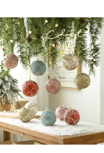 Detail of 8cm Christmas ball with gold grid pattern and glitter finish on pine branch