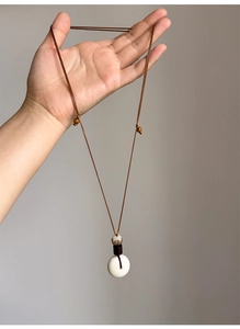 Détail du collier Bodhi avec pendentif lotus sculpté et cordon marron réglable