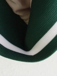 Detail of forest green and white striped ribbed knit collar with beige lining on jacket