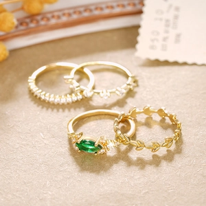 Detalle macro del set de 4 anillos con piedra marquesa verde y textura de hoja dorada