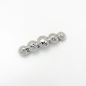 Macro view of silver metal hair clip with five polished spherical beads and hammered texture