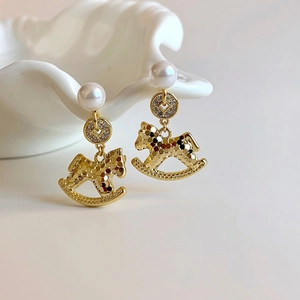 Macro detail of 18K gold plated rocking horse earrings with pearls and crystals