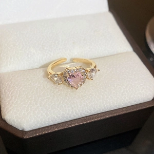 Gold open ring featuring a pink heart stone and side accents on a white cushion