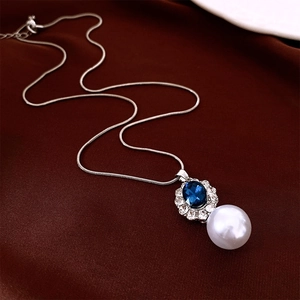 Detail of silver snake chain necklace with blue oval gemstone and white pearl pendant