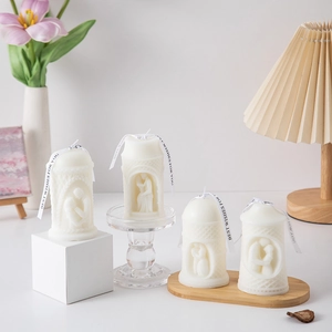 Macro view of hand-carved cream white pillar candle featuring romantic couple embrace