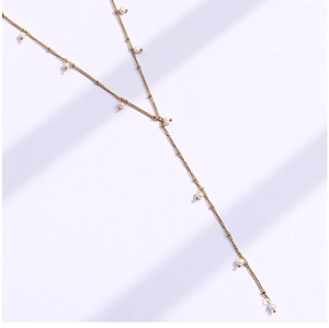 Close-up of gold Y-shaped tassel necklace featuring elegant white round pearls