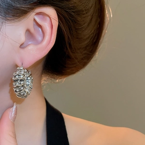 Close-up of a silver U-shaped hoop earring with pavé rhinestones on a female model