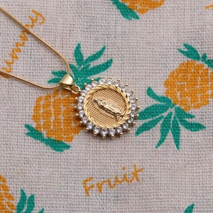 Close-up of Virgin Mary gold pendant necklace with cubic zirconia and snake chain