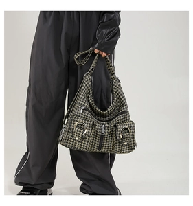 Detail of houndstooth crossbody bag featuring multiple zipper pockets and metal hardware