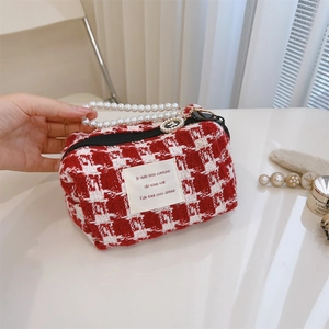 Detail of red and white houndstooth tweed cosmetic bag with elegant pearl handle