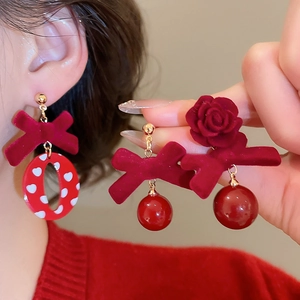Détail de boucles d'oreilles nœud en velours rouge avec rose et motifs de cœur festifs