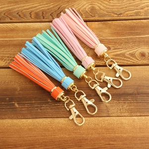 Macro detail of multi-colored leather tassels with golden lobster clasps on wood