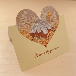 Detailed view of 3D heart-shaped greeting card with oil painting house design on desk