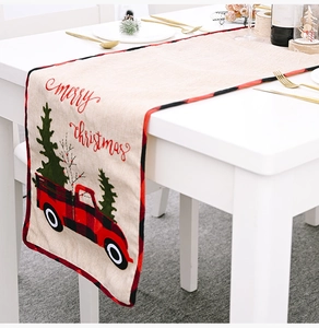 Christmas table runner with red truck and tree on white table with gold cutlery