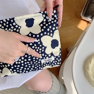 Detailed texture of cotton makeup bag with dark blue floral print and white brand label