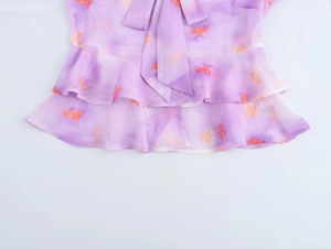 Detail of purple tie-dye chiffon top with orange floral print and tiered ruffle hem