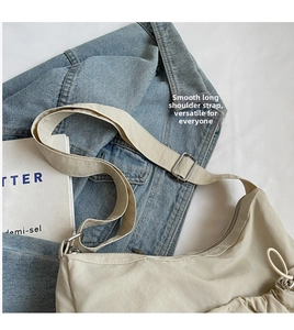 Detail of cream nylon crossbody bag with side pleats and adjustable metal strap buckle