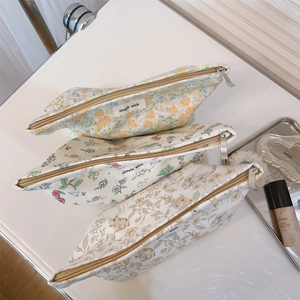Close-up of floral and rabbit print canvas makeup bags with metal zippers on white surface