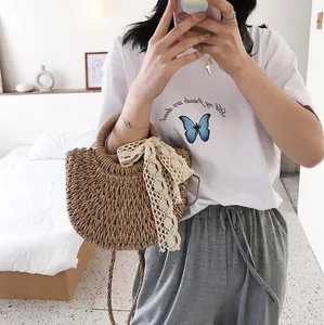 Handmade woven straw handbag with beige lace bow charm shown in a cozy bedroom setting