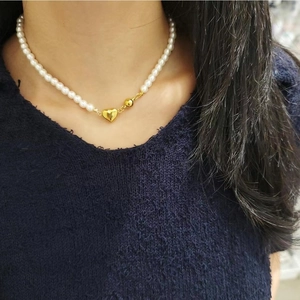 Close-up of pearl necklace with gold heart pendant worn on a model's neck