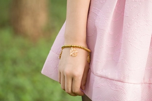 Macro detail of golden Hamsa hand charms on a beaded stainless steel stretch bracelet