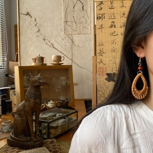 Handmade woven rattan teardrop earrings with wood beads in bohemian style on a model