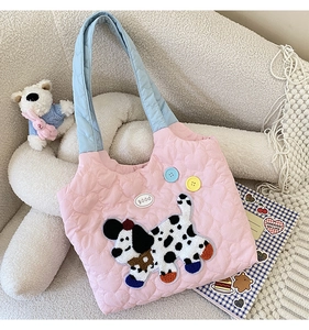 Detail of pink quilted handbag with heart stitching and cute puppy embroidery on a sofa