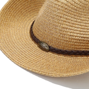 Detail view of woven straw hat featuring dark brown leather band and brass bull emblem