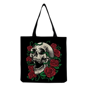 Close-up of gothic skull and red rose floral print on black canvas tote bag surface
