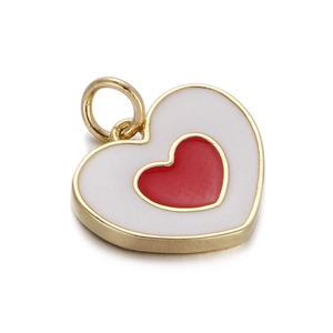 Macro shot of a heart-shaped pendant with gold frame, white enamel and a tiny red heart