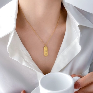 Detail of elegant gold rectangle pendant necklace with three zircon stars on a model