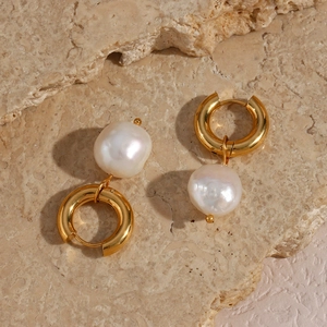 Gros plan de boucles d'oreilles dorées avec perles baroques sur pierre naturelle