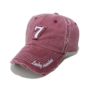 Close-up of distressed vintage red baseball cap with white number 7 and lucky embroidery