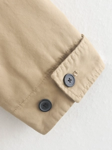 Macro detail of khaki jacket cuff featuring high-density fabric and dark buttons