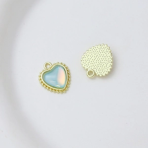 Macro detail of heart-shaped charm with blue faux opal inlay and golden beaded edge