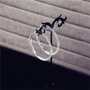 Macro shot of oversized silver hoop earrings with clear rhinestones on black stand