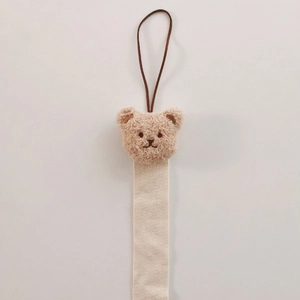 Detail of plush bear head with beige herringbone ribbon and hanging loop for hair clips