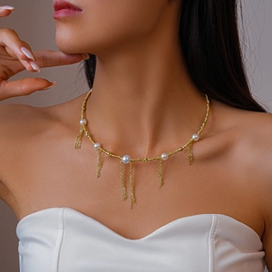 Detail of gold beaded necklace with imitation pearls and elegant fringe tassels