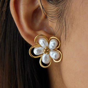 Close-up of gold 18K flower earrings with white opal petals worn by a model