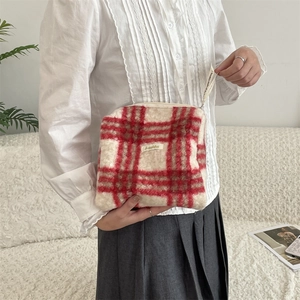 Detail van rood en beige geruite fleece make-uptas met zachte textuur en merklabel