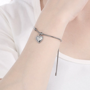 Detail of silver heart charm on adjustable snake chain bracelet with polished finish