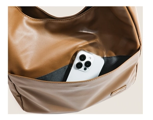 Close-up of brown leather shoulder bag exterior pocket showing phone storage capacity