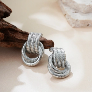 Detailed close-up of 18K silver-plated multi-layer twisted rope earrings on a stone base