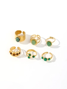 Detail of six gold-tone stainless steel rings with colorful turquoise and tiger eye stones