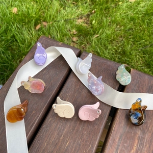 Détail des barrettes à cheveux en acétate en forme d'ailes avec perles et strass sur bois